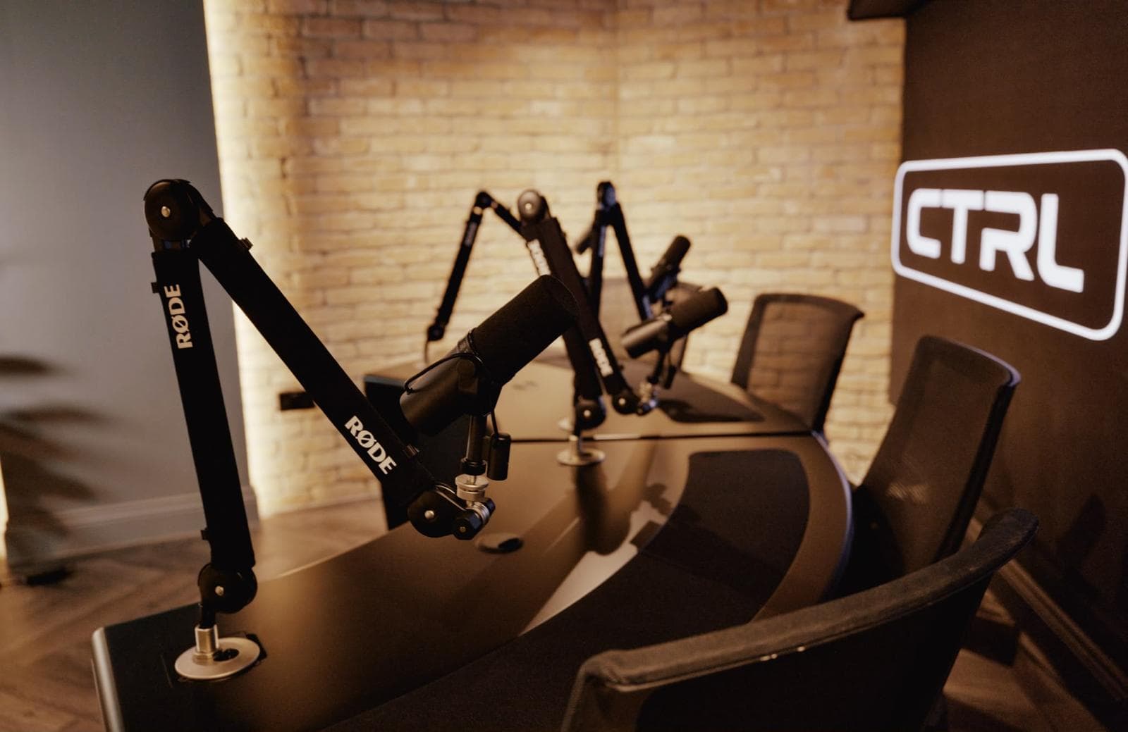 CTRL Old Street podcast recording desk with Rode microphone arms and warm brick studio lighting in Islington N1